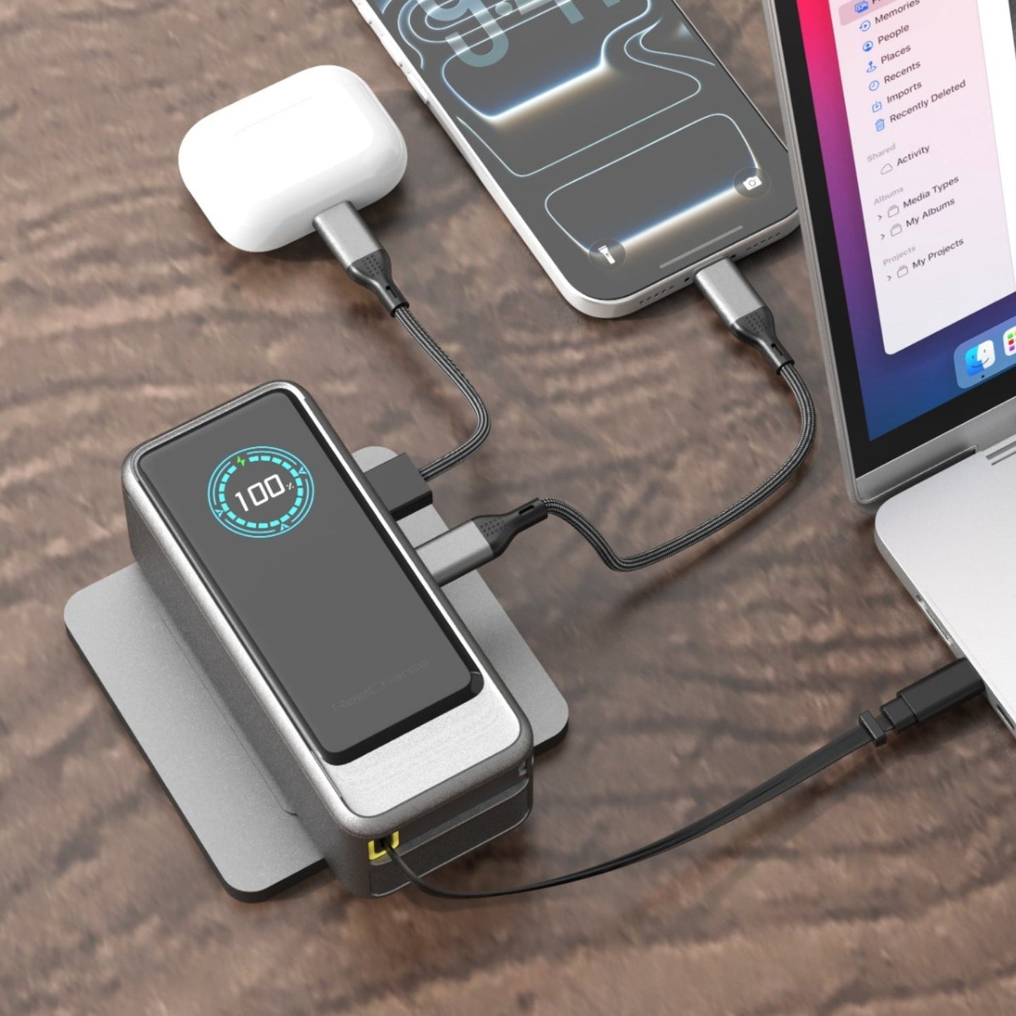ReelPro 45W power bank on a wooden desk charging a phone, AirPods and a MacBook at the same time