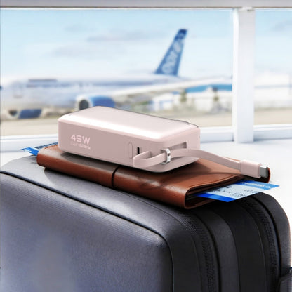 Pink ReelCharge ReFlextion 45W power bank resting on a suitcase at an airport gate with an aircraft outside the window