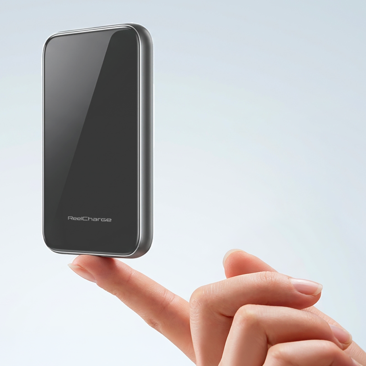 Hand balancing the Gray tempered glass ReelSafe 5,000 mAh power bank on a fingertip to show its light weight