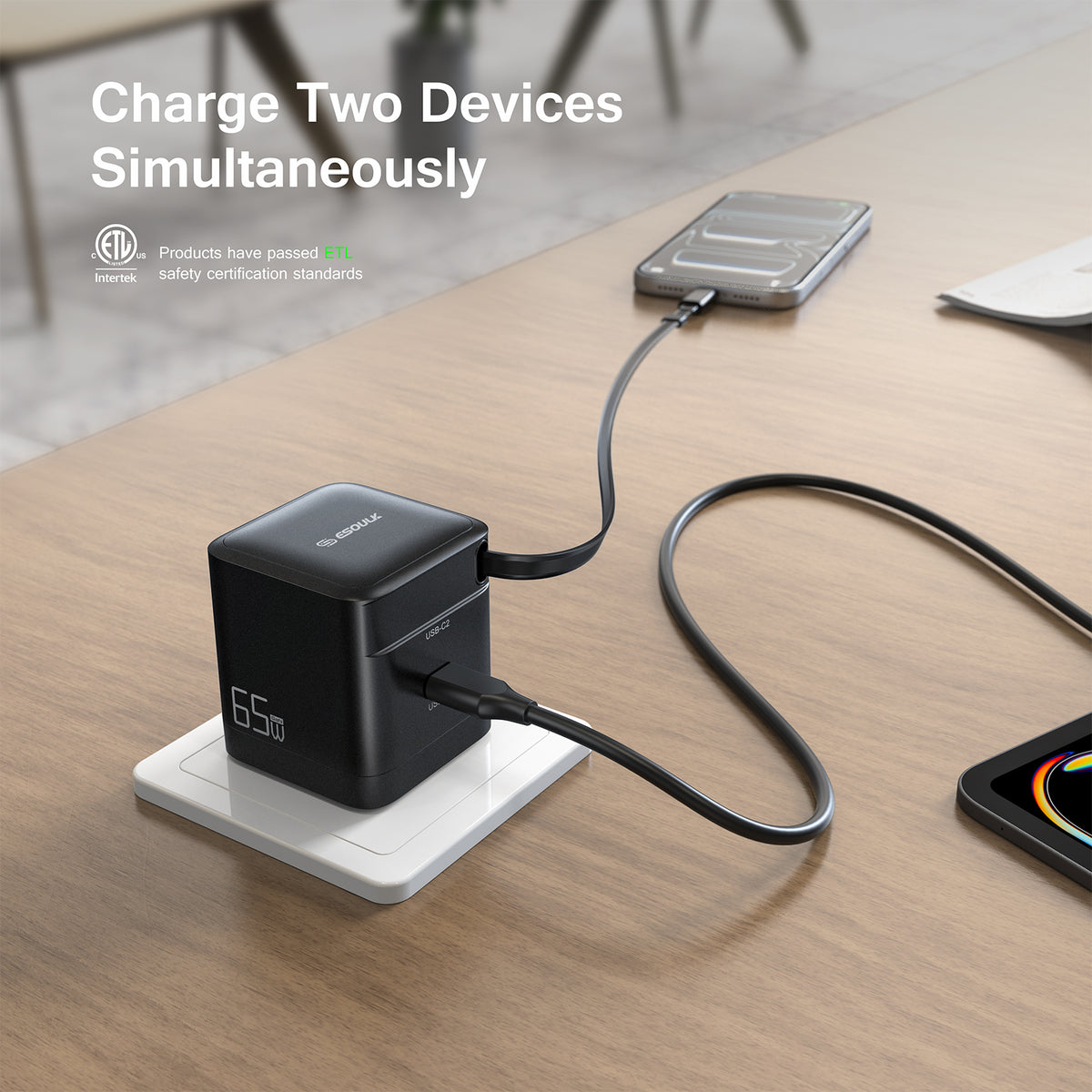ESOULK 65W charger on a desk outlet charging a laptop and a phone at the same time