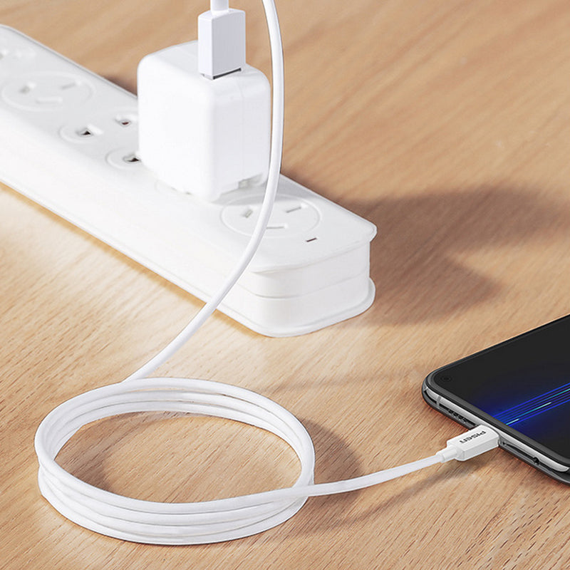 White PISEN USB-A to USB-C cable charging a phone from a wall adapter in a power strip on a wooden desk