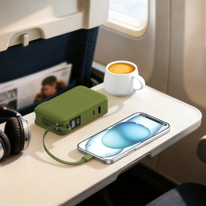 Green ReelCharge Flex 65W power bank charging a phone on an airplane tray table