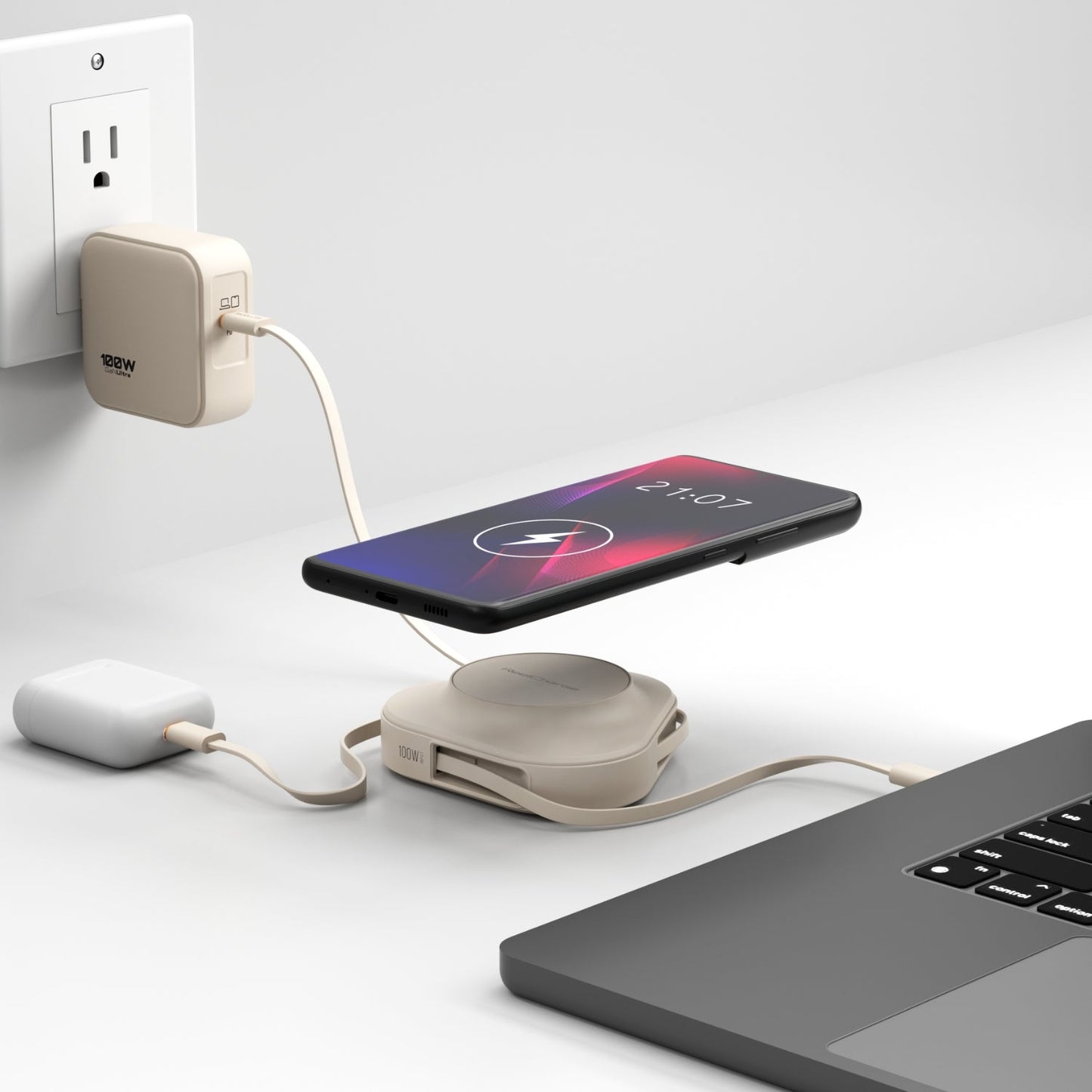 Sand ReelCharge 100W power station on a desk charging a phone wirelessly beside a laptop and wall charger
