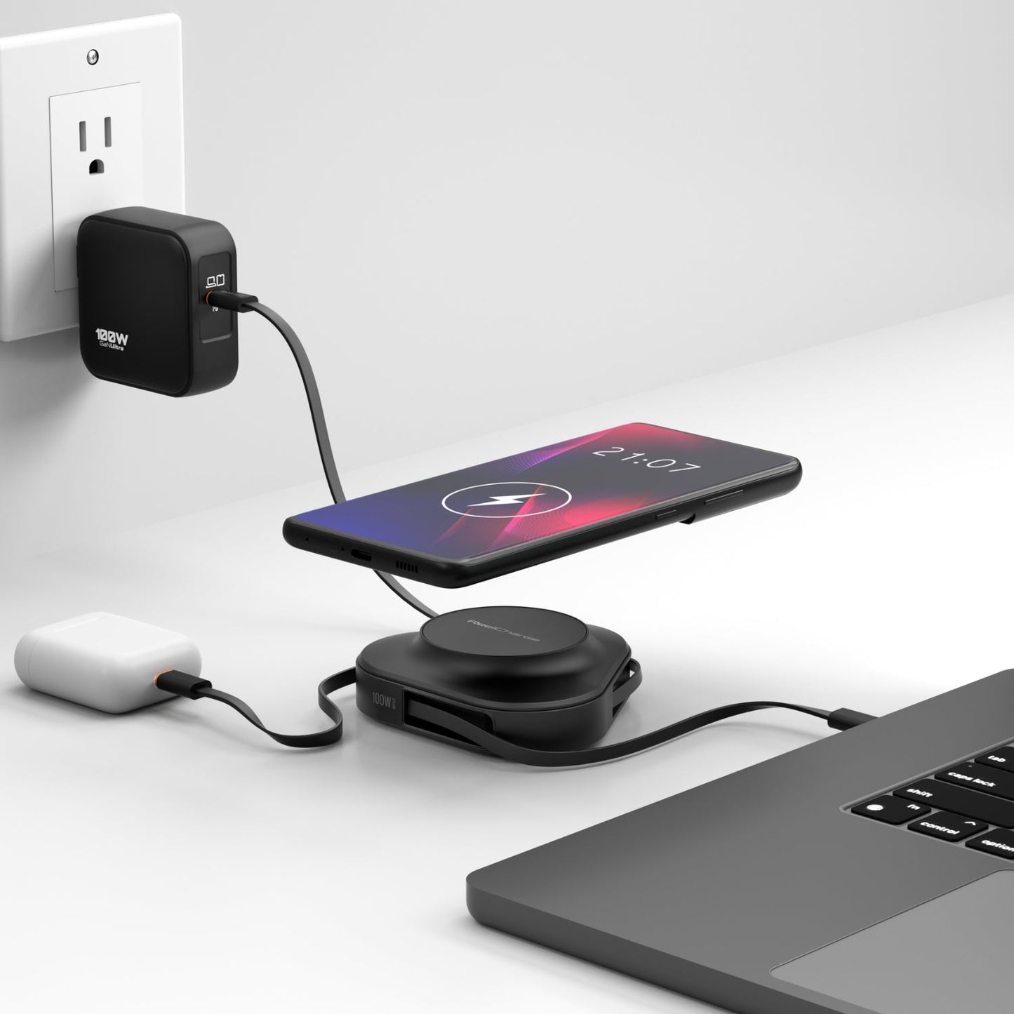 Black ReelCharge 100W power station on a desk charging a phone wirelessly next to a laptop