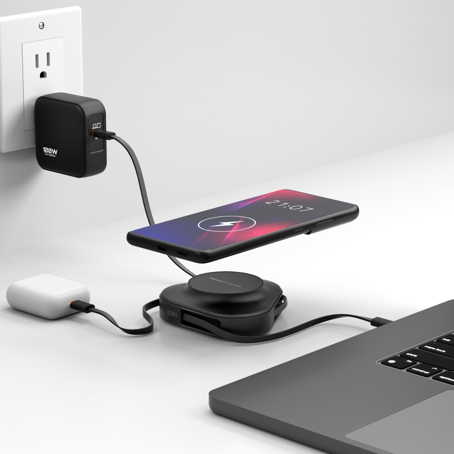 Black ReelCharge 100W power station on a desk charging a phone wirelessly next to a laptop