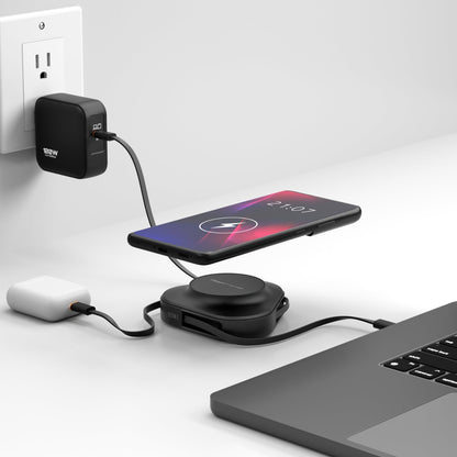Black ReelCharge 100W power station on a desk charging a phone wirelessly next to a laptop